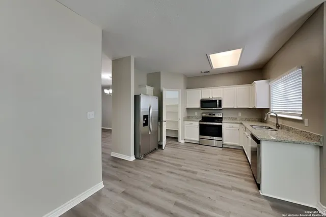 a kitchen with granite countertop a refrigerator and a stove top oven