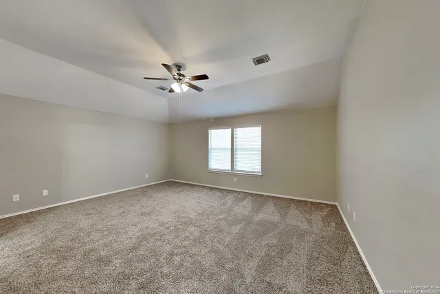 an empty room with a chandelier fan and windows