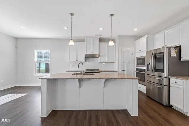 a kitchen with stainless steel appliances granite countertop a sink a stove a refrigerator and island with wooden floor