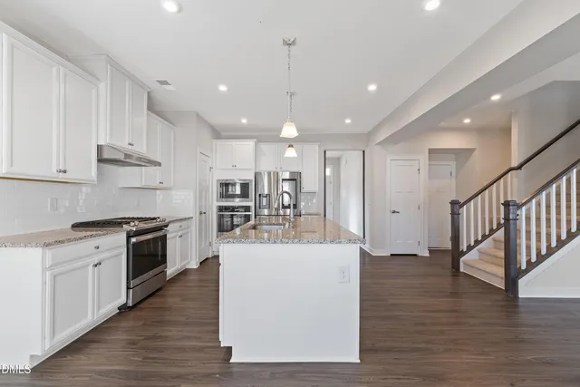 a view of kitchen with kitchen island a stove a sink and a refrigerator
