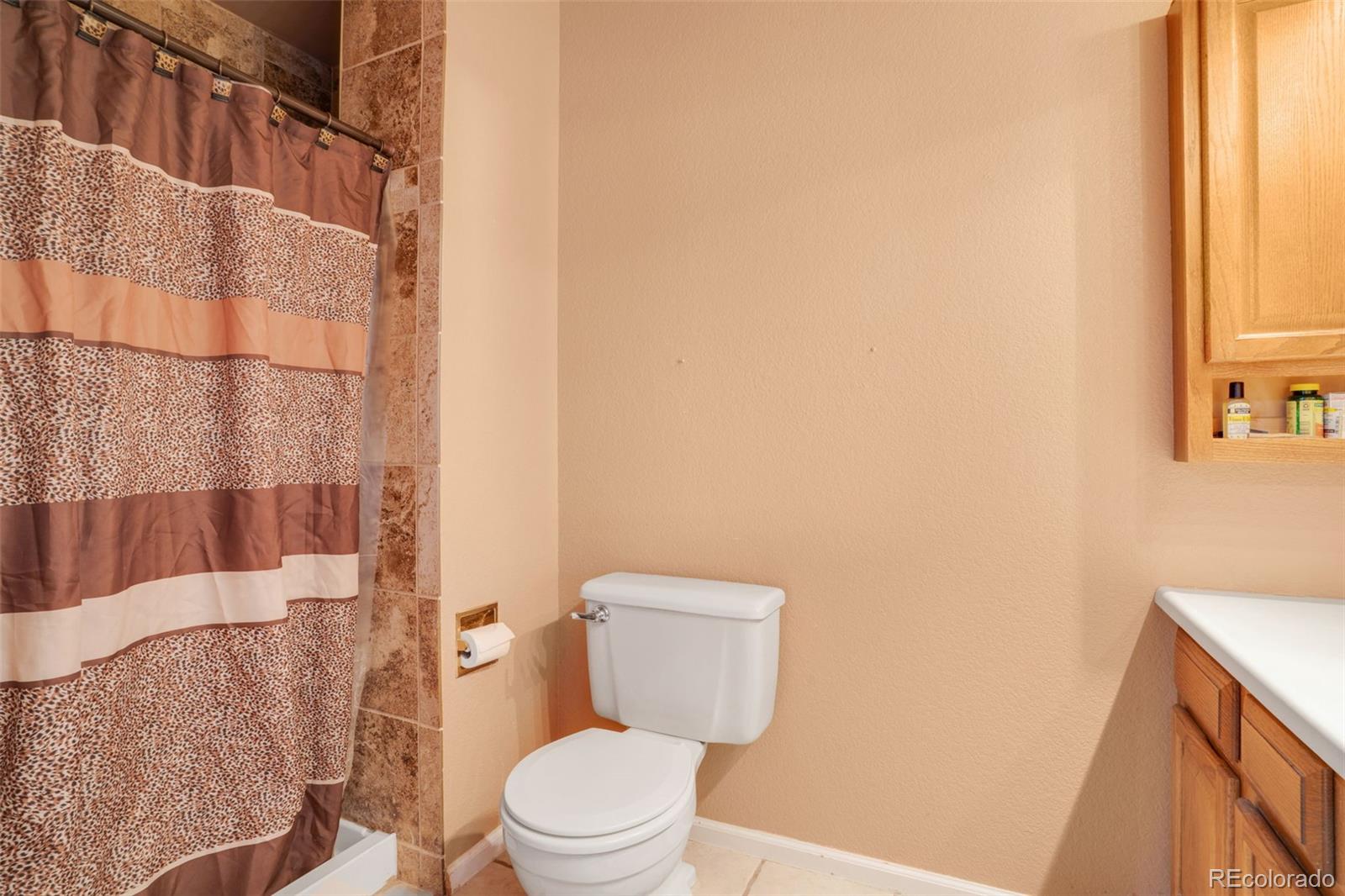 210 South Elm Street Bennett, CO 80102 - Photo 9 of 31 a bathroom with a toilet and a shower curtain