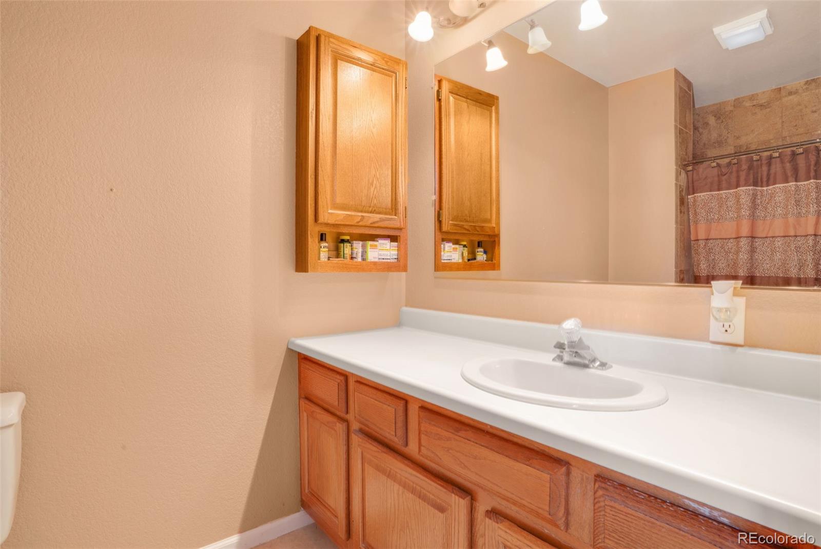 210 South Elm Street Bennett, CO 80102 - Photo 10 of 31 a bathroom with a sink and a mirror