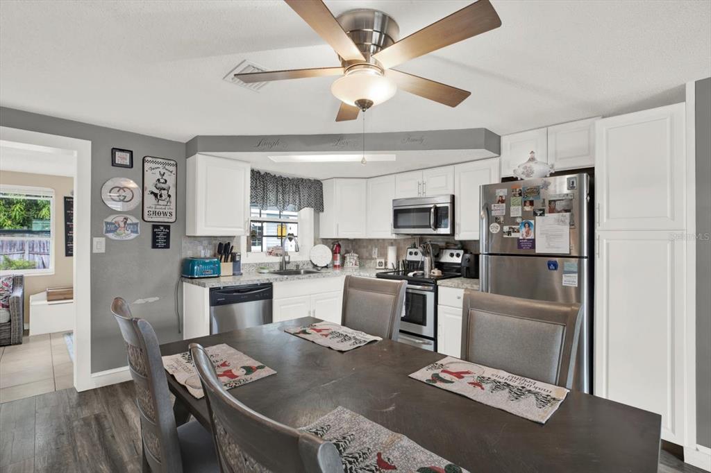 7415 Mayfield Drive Port Richey, FL 34668 - Photo 3 of 17 a kitchen with stainless steel appliances kitchen island granite countertop a refrigerator a stove a sink dishwasher a dining table and chairs with wooden floor