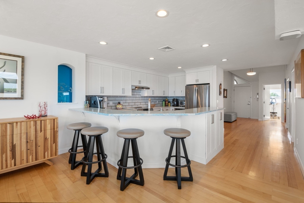 66 Glades Road, Unit 8 Scituate, MA 02066 - Photo 15 of 27 a kitchen with stainless steel appliances granite countertop a table chairs refrigerator and a sink