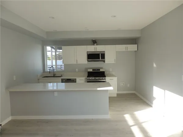 a large kitchen with stainless steel appliances a sink a stove a microwave a sink and cabinets