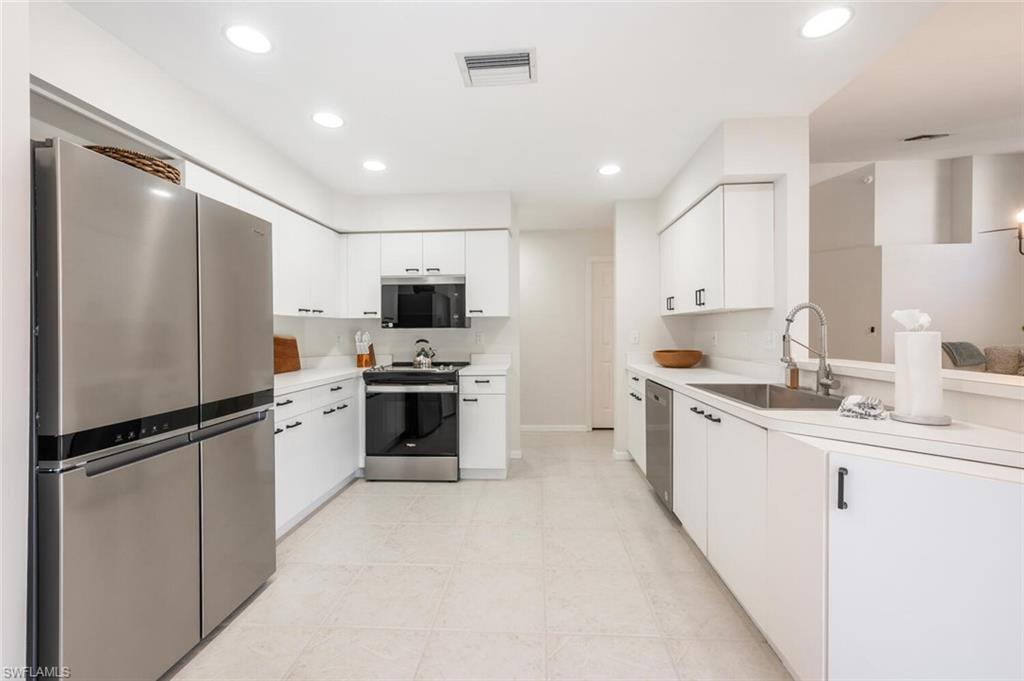 2835 Mizzen Way Naples, FL 34109 - Photo 11 of 46 a kitchen with white cabinets and stainless steel appliances