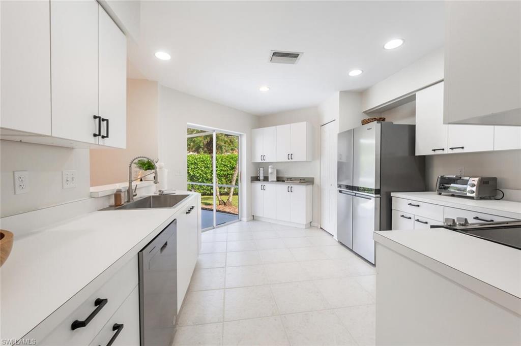 2835 Mizzen Way Naples, FL 34109 - Photo 9 of 46 a kitchen with white cabinets and stainless steel appliances