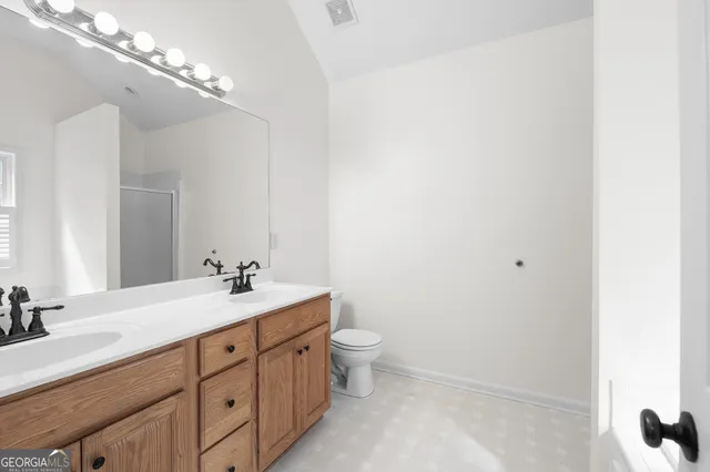 a bathroom with a double vanity sink toilet and a mirror