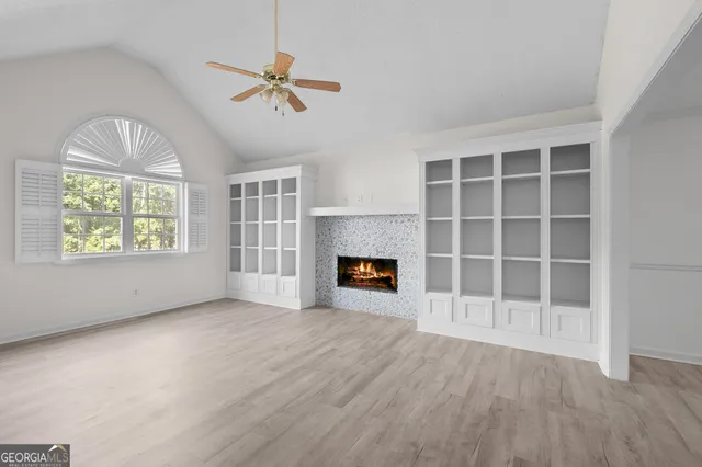 an empty room with windows a fireplace a ceiling fan and windows