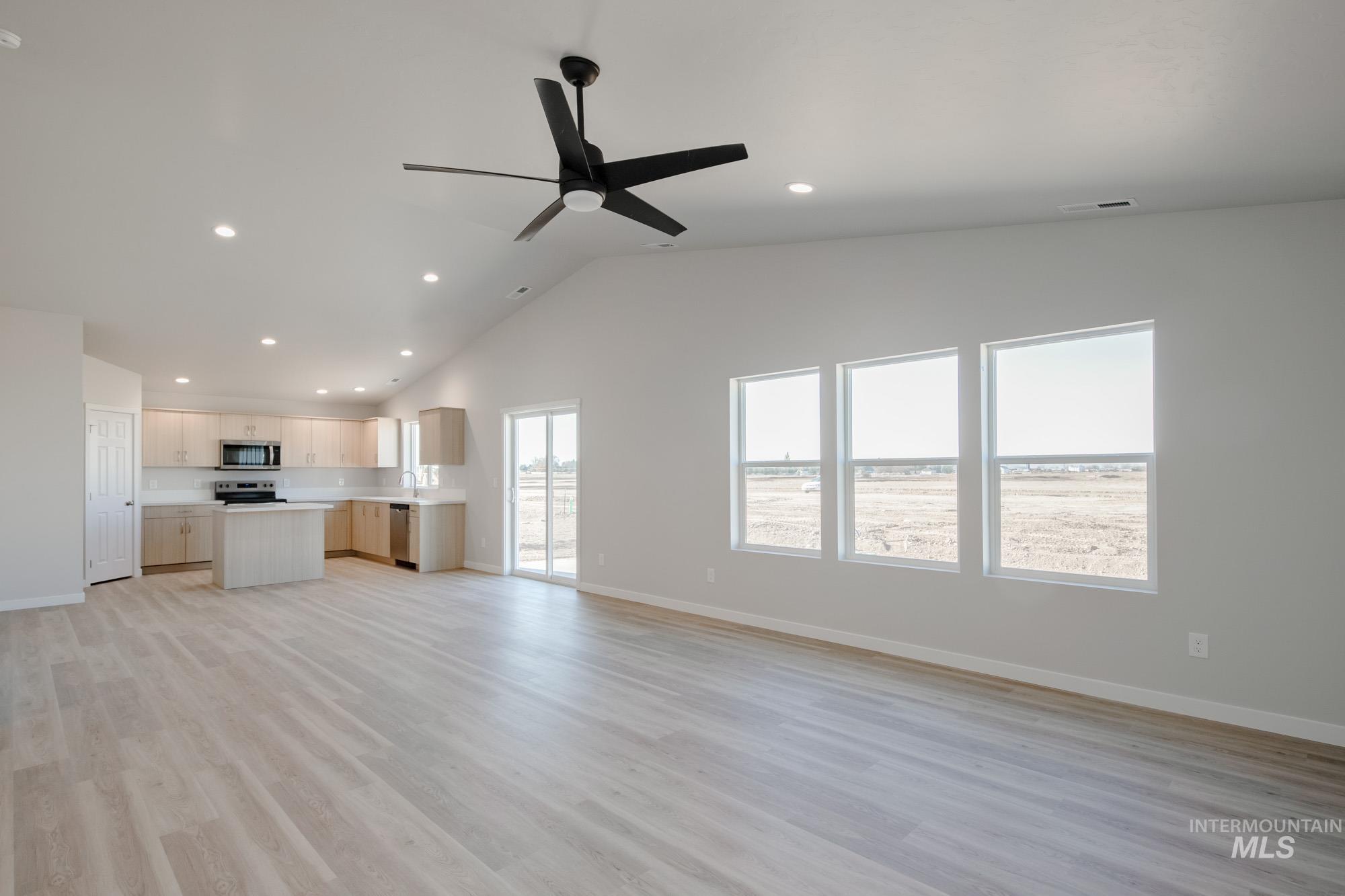 7472 South Menzingers Avenue Meridian, ID 83642 - Photo 11 of 22 Unfurnished living room featuring light wood-style flooring, recessed lighting, ceiling fan, and high vaulted ceiling