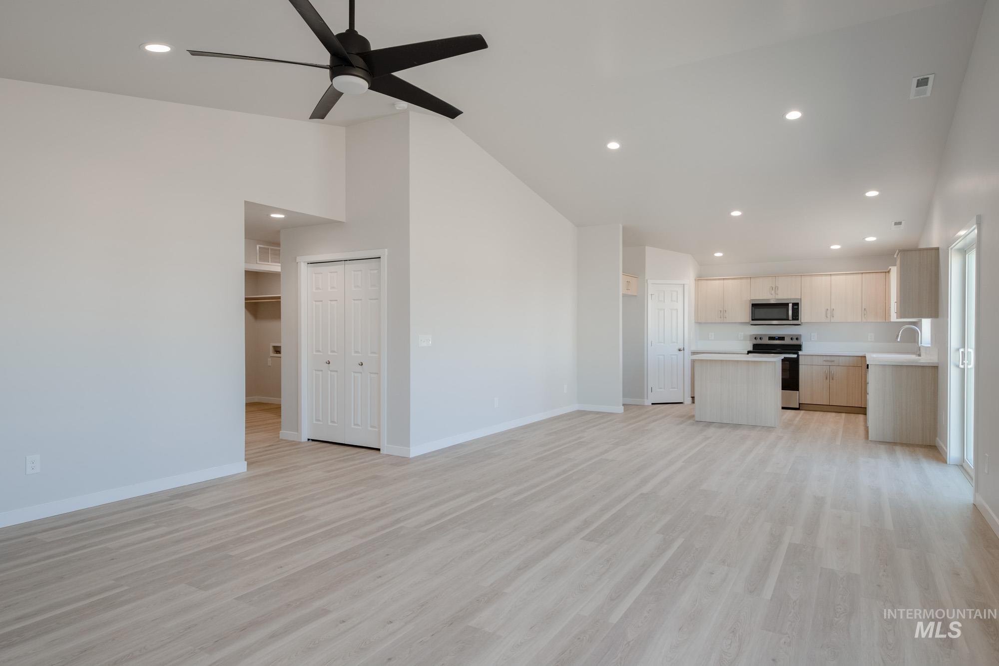 7472 South Menzingers Avenue Meridian, ID 83642 - Photo 13 of 22 Unfurnished living room featuring recessed lighting, light wood finished floors, high vaulted ceiling, and a ceiling fan