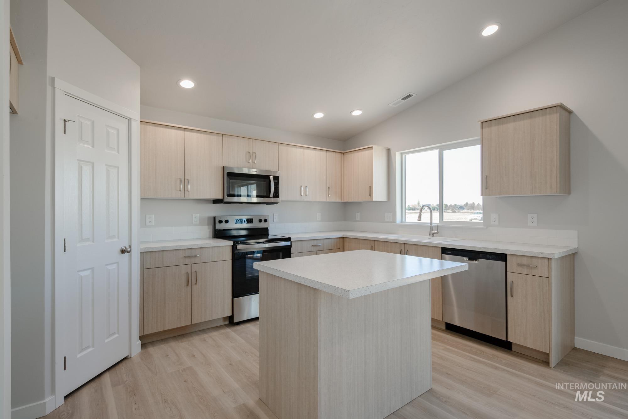 7472 South Menzingers Avenue Meridian, ID 83642 - Photo 3 of 22 Kitchen with light brown cabinets, stainless steel appliances, light countertops, a kitchen island, and light wood-style flooring