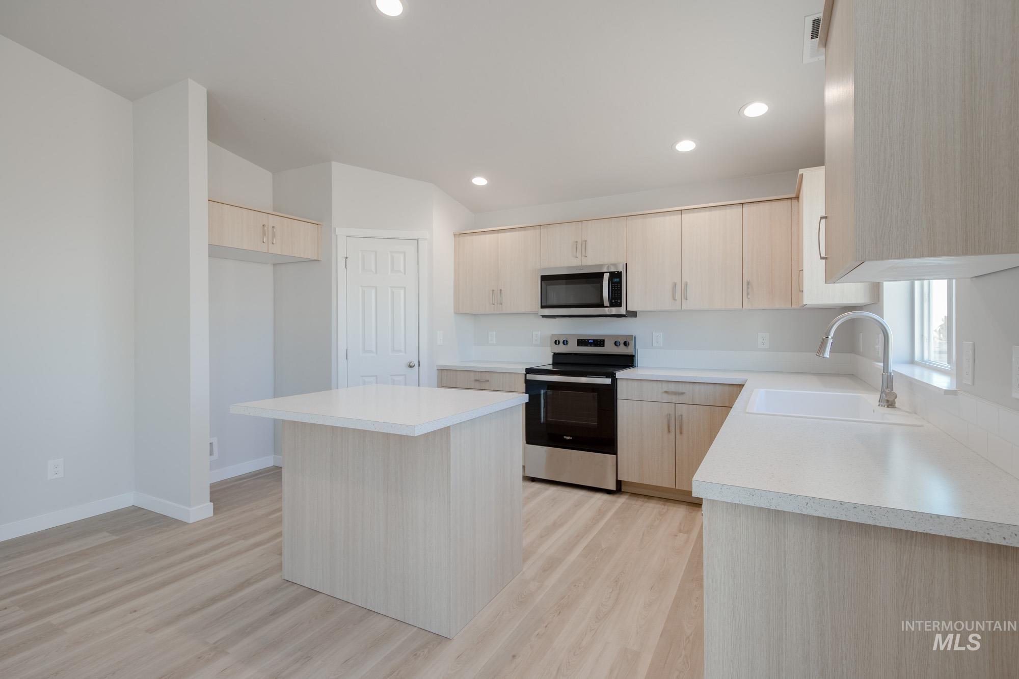 7472 South Menzingers Avenue Meridian, ID 83642 - Photo 5 of 22 Kitchen featuring light brown cabinetry, appliances with stainless steel finishes, light countertops, a center island, and light wood finished floors