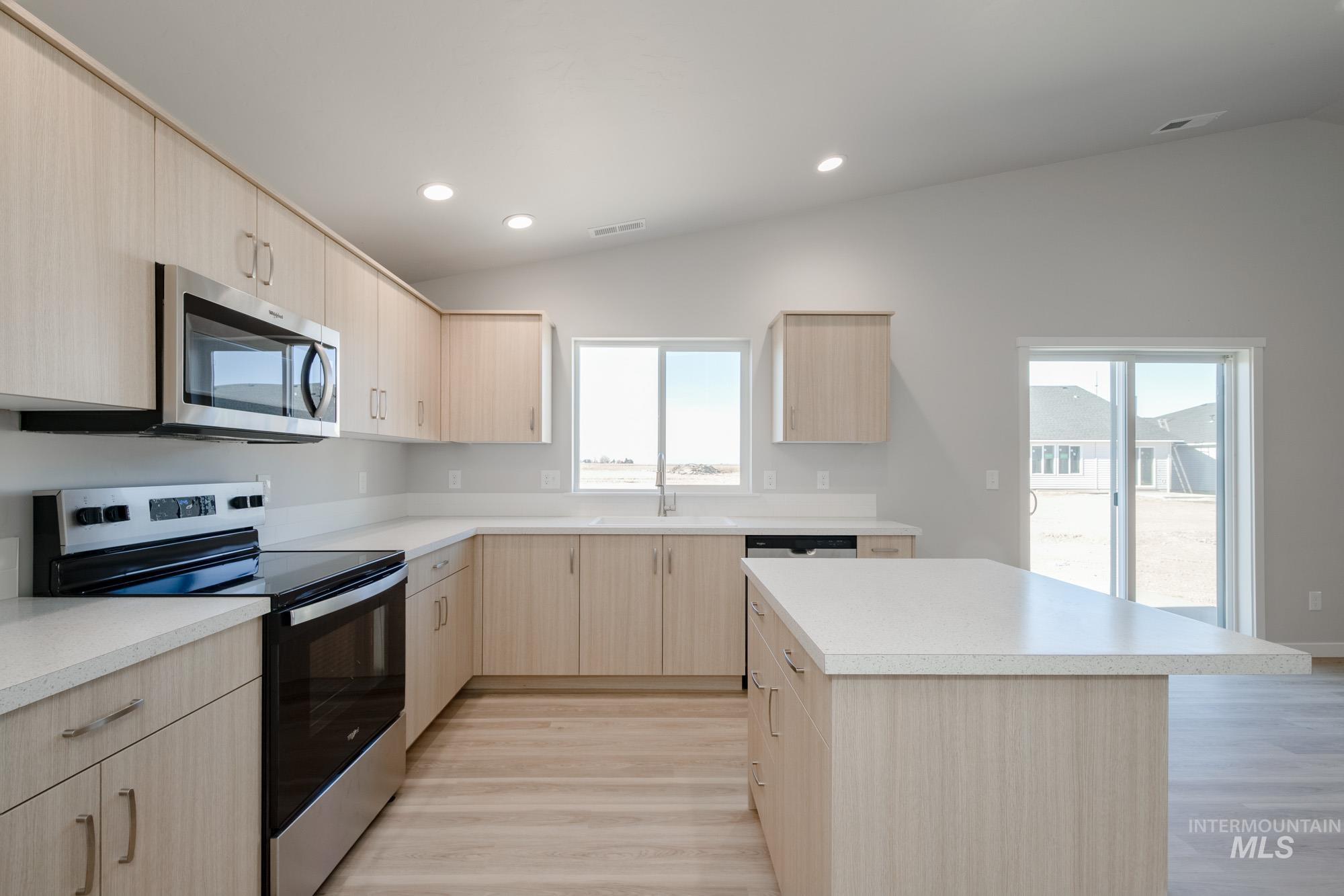 7472 South Menzingers Avenue Meridian, ID 83642 - Photo 7 of 22 Kitchen featuring light brown cabinetry, appliances with stainless steel finishes, lofted ceiling, light countertops, and recessed lighting