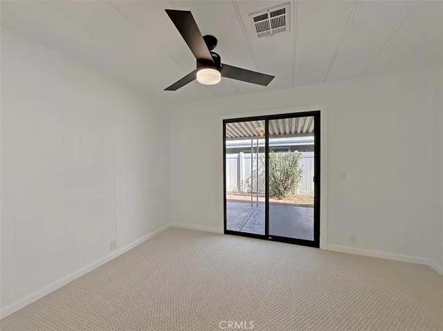 an empty room with windows and ceiling fan