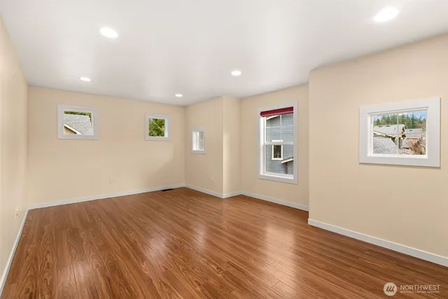 a view of an empty room with wooden floor and a window
