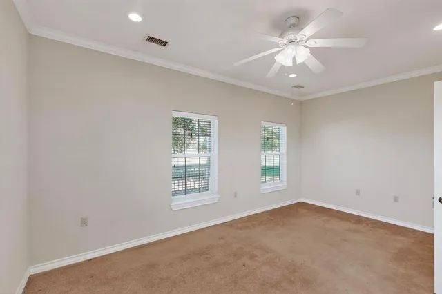 an empty room with windows and ceiling fan