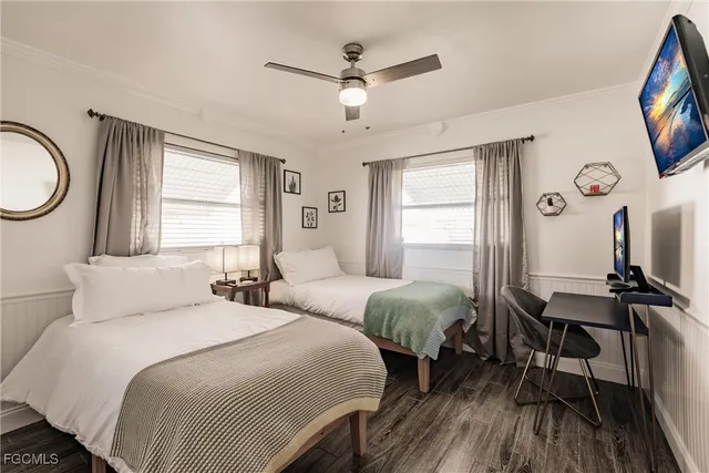 a bedroom with two beds a chandelier and a window