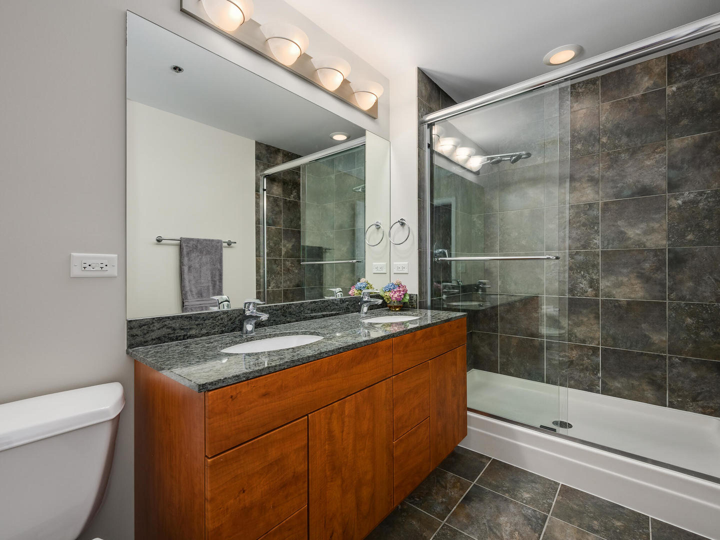 2303 South Michigan Avenue, Unit 305 Chicago, IL 60616 - Photo 16 of 22 a bathroom with a granite countertop sink a toilet a mirror and shower