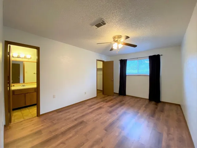 a view of empty room with wooden floor and fan