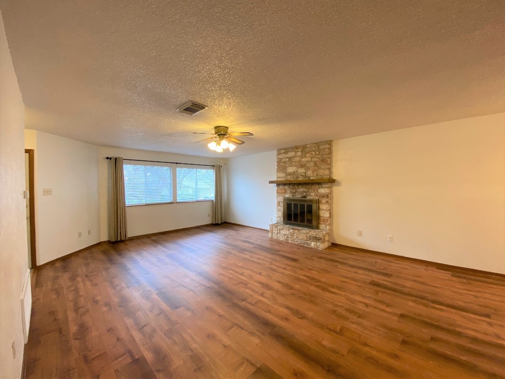 5502 Honey Dew Terrace Austin, TX 78749 - Photo 5 of 18 an empty room with wooden floor fireplace and windows