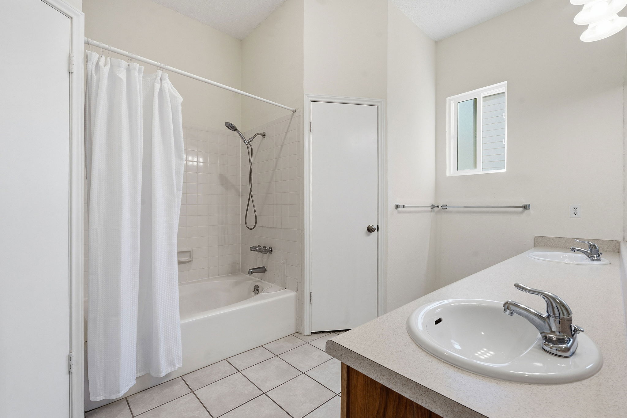 14818 Yellowleaf Trail Austin, TX 78728 - Photo 11 of 26 Bathroom featuring a white bathtub with subway tile surround, two integrated sinks, individual chrome faucets, wood-finish vanity, and a window