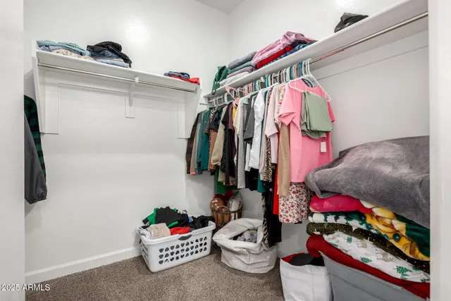 a view of walk in closet with clothes and shoes