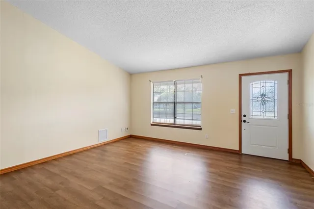 an empty room with wooden floor and windows