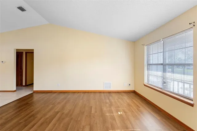 an empty room with wooden floor fan and windows