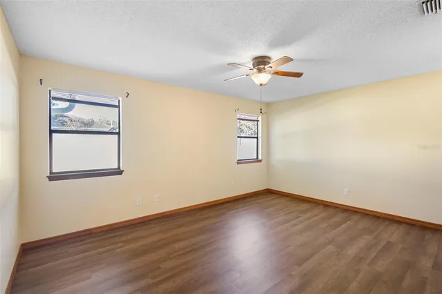 an empty room with wooden floor closet and fan