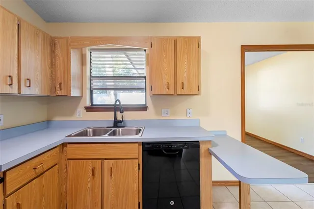 a view of a refrigerator in kitchen and an empty room with windows