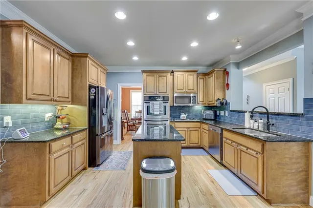 a kitchen with stainless steel appliances granite countertop a sink dishwasher stove and refrigerator with wooden floor