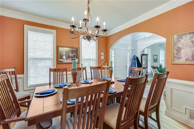 a view of a dining room with furniture a chandelier and large windows