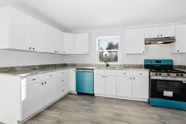 a kitchen with granite countertop white cabinets and stainless steel appliances