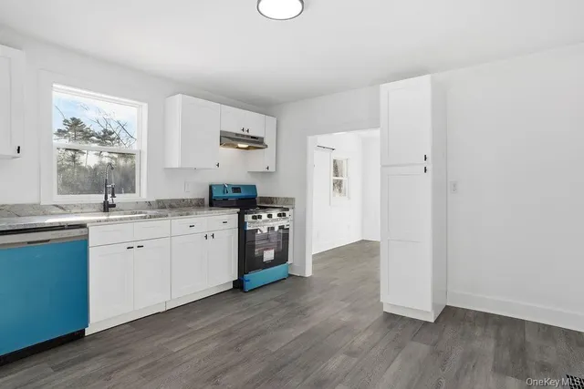 a kitchen with granite countertop a sink cabinets and wooden floor