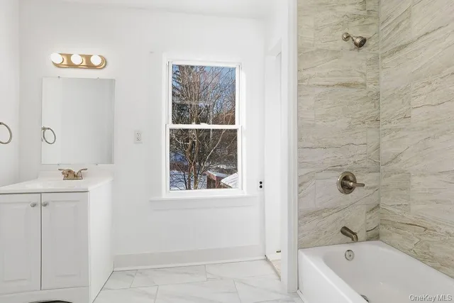 a bathroom with a tub a sink and a window