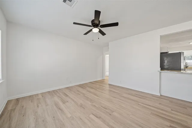 a view of a room with wooden floor ceiling fan and window