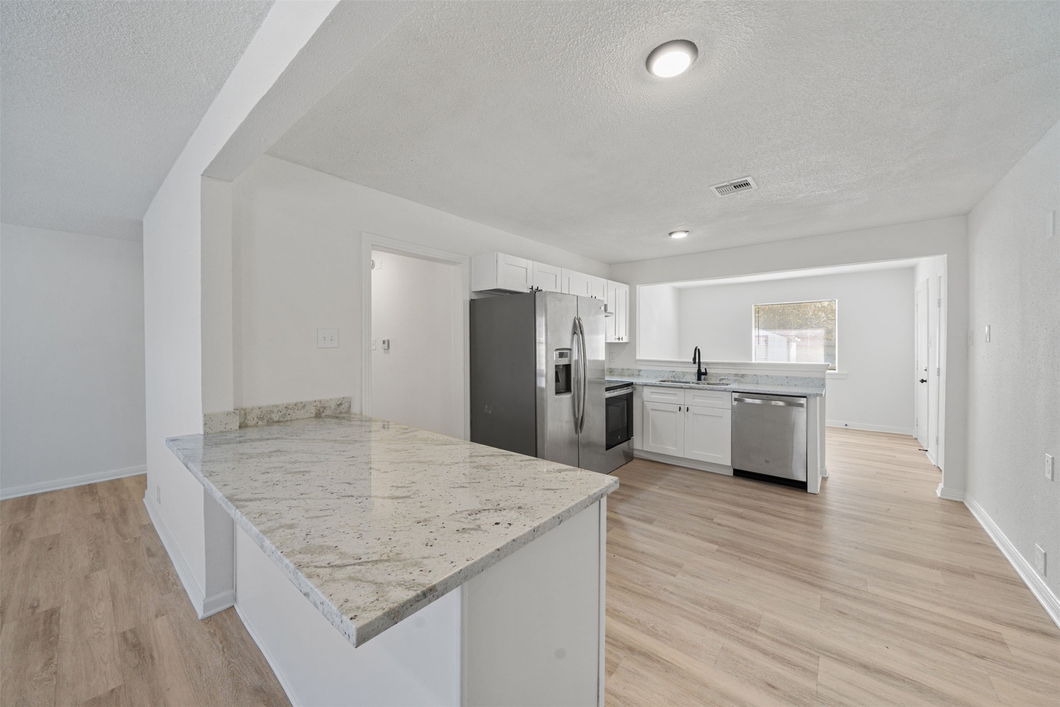 4601 West 43rd Street Houston, TX 77092 - Photo 7 of 40 a kitchen with stainless steel appliances granite countertop a sink dishwasher a refrigerator and white cabinets with wooden floor