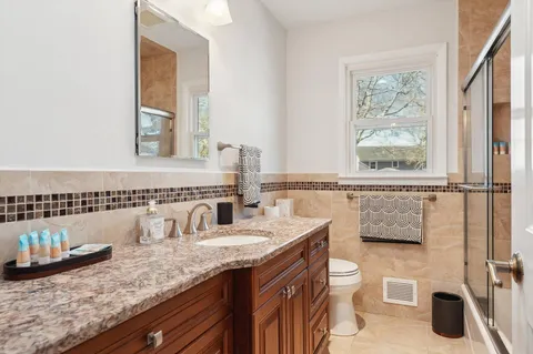 a bathroom with a granite countertop sink a large mirror and a bathtub