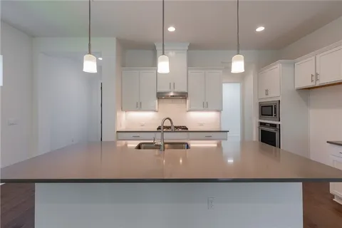 a view of a kitchen with kitchen island a sink stainless steel appliances and cabinets