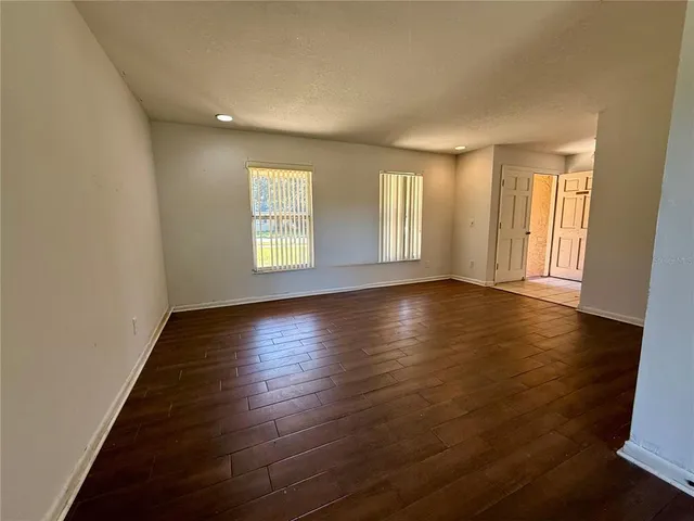 an empty room with wooden floor and windows with curtains view