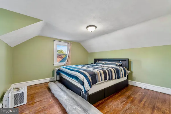 a spacious bedroom with a bed and wooden floor