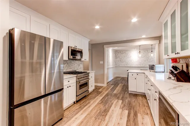 a kitchen with a refrigerator a sink dishwasher and a stove top oven with wooden floor