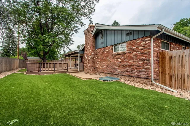 a view of backyard with wooden fence and large trees