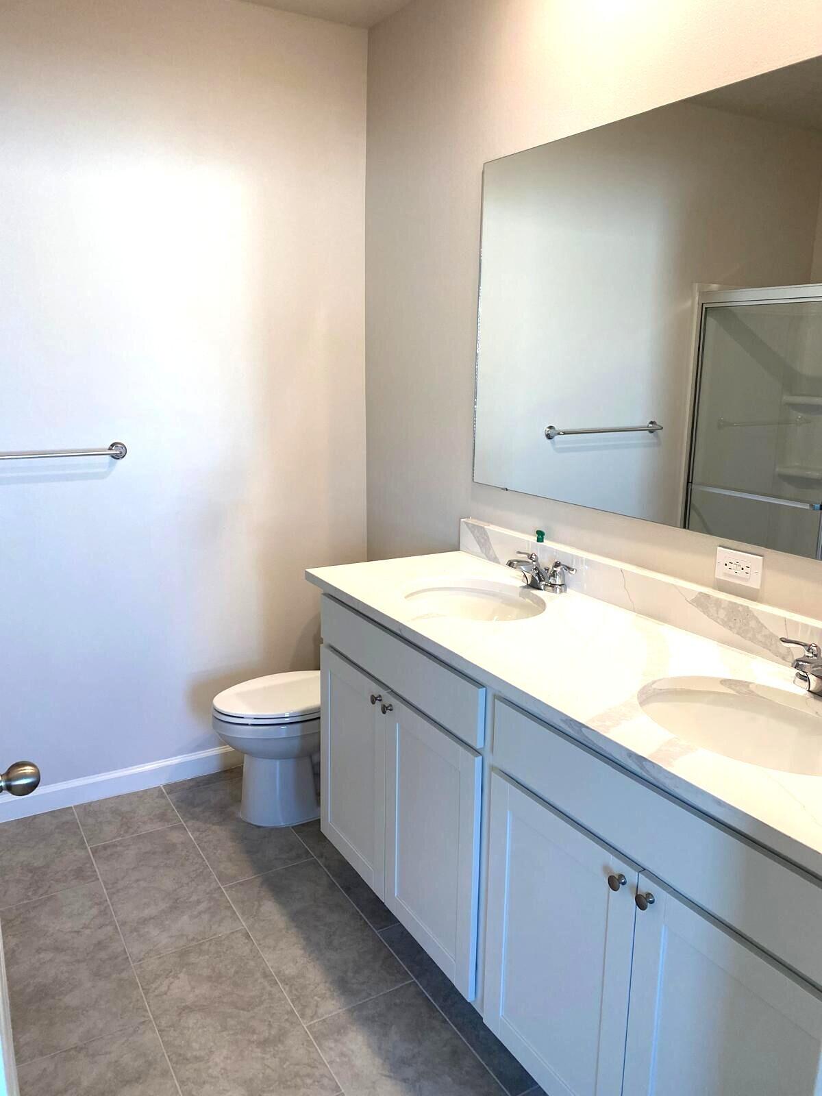 9622 Seaspray Drive Fort Pierce, FL 34945 - Photo 23 of 32 a bathroom with a sink a toilet and a mirror