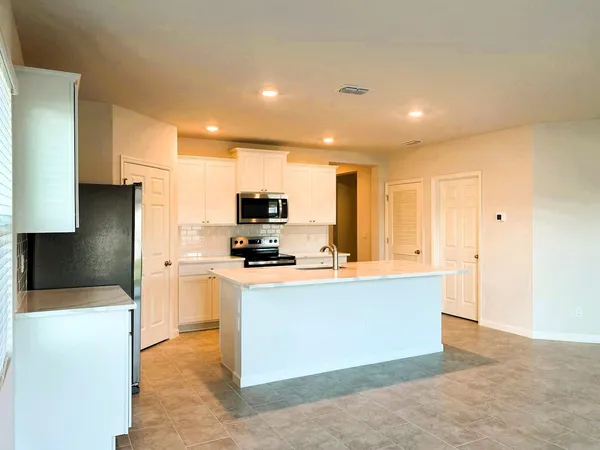 a large kitchen with stainless steel appliances a stove a refrigerator a sink a center island and couches