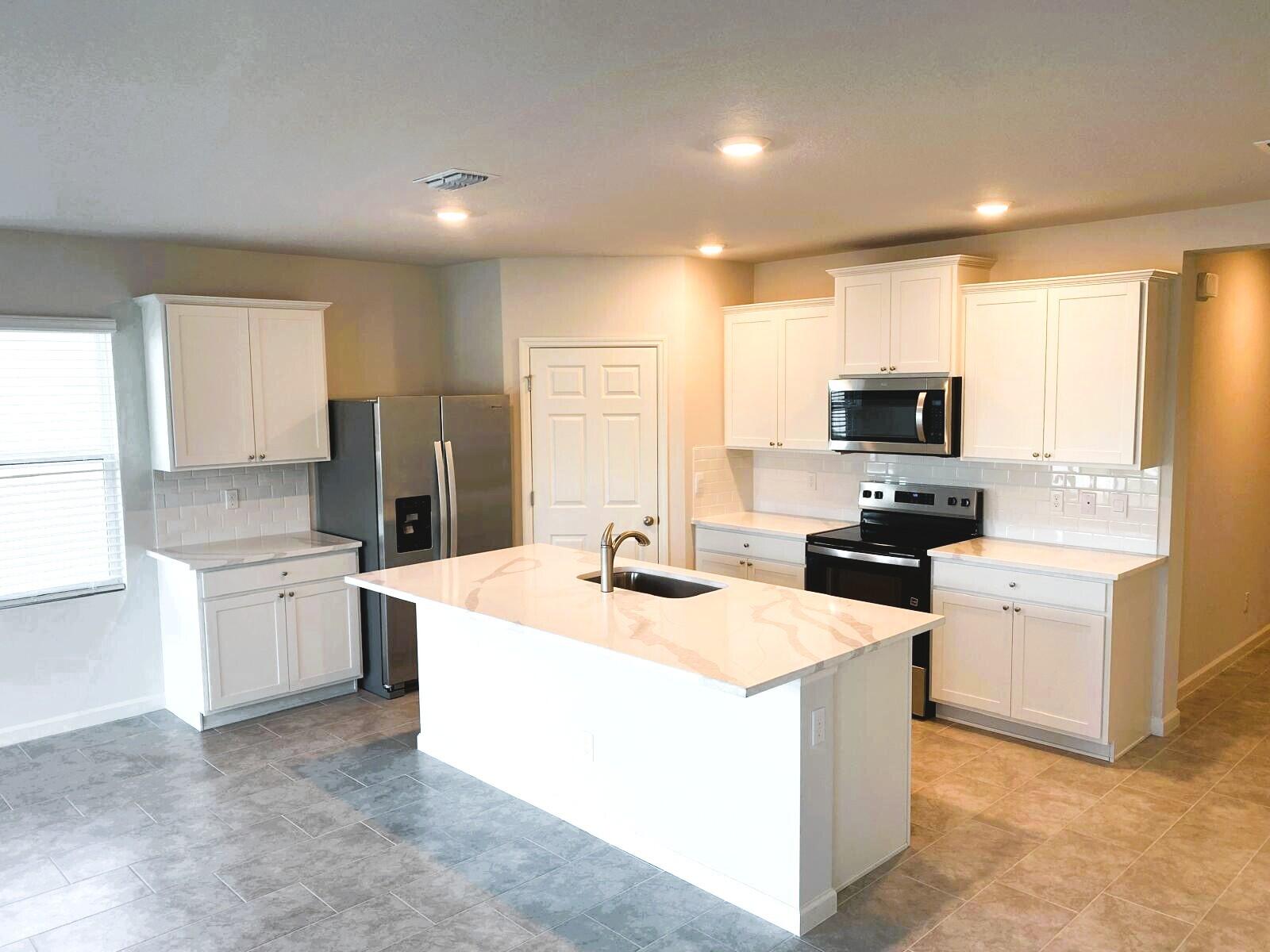 9622 Seaspray Drive Fort Pierce, FL 34945 - Photo 6 of 32 a kitchen with stainless steel appliances a stove a sink dishwasher a refrigerator and white cabinets with wooden floor