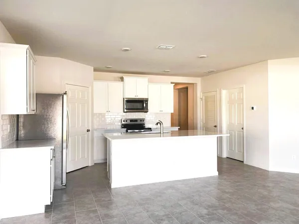a large white kitchen with kitchen island a sink a stove and a refrigerator