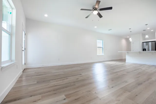 a view of an empty room with wooden floor and a window