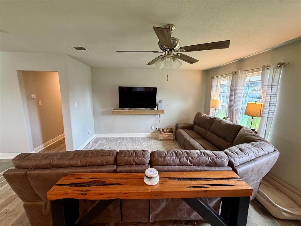 619 Mansfield Road Cleburne, TX 76031 - Photo 5 of 19 Living area featuring light gray wall paint, wood-finish flooring, and a ceiling fan with integrated lighting